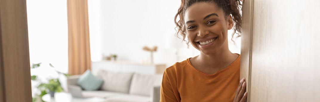 A Millennial opens the door to her home.